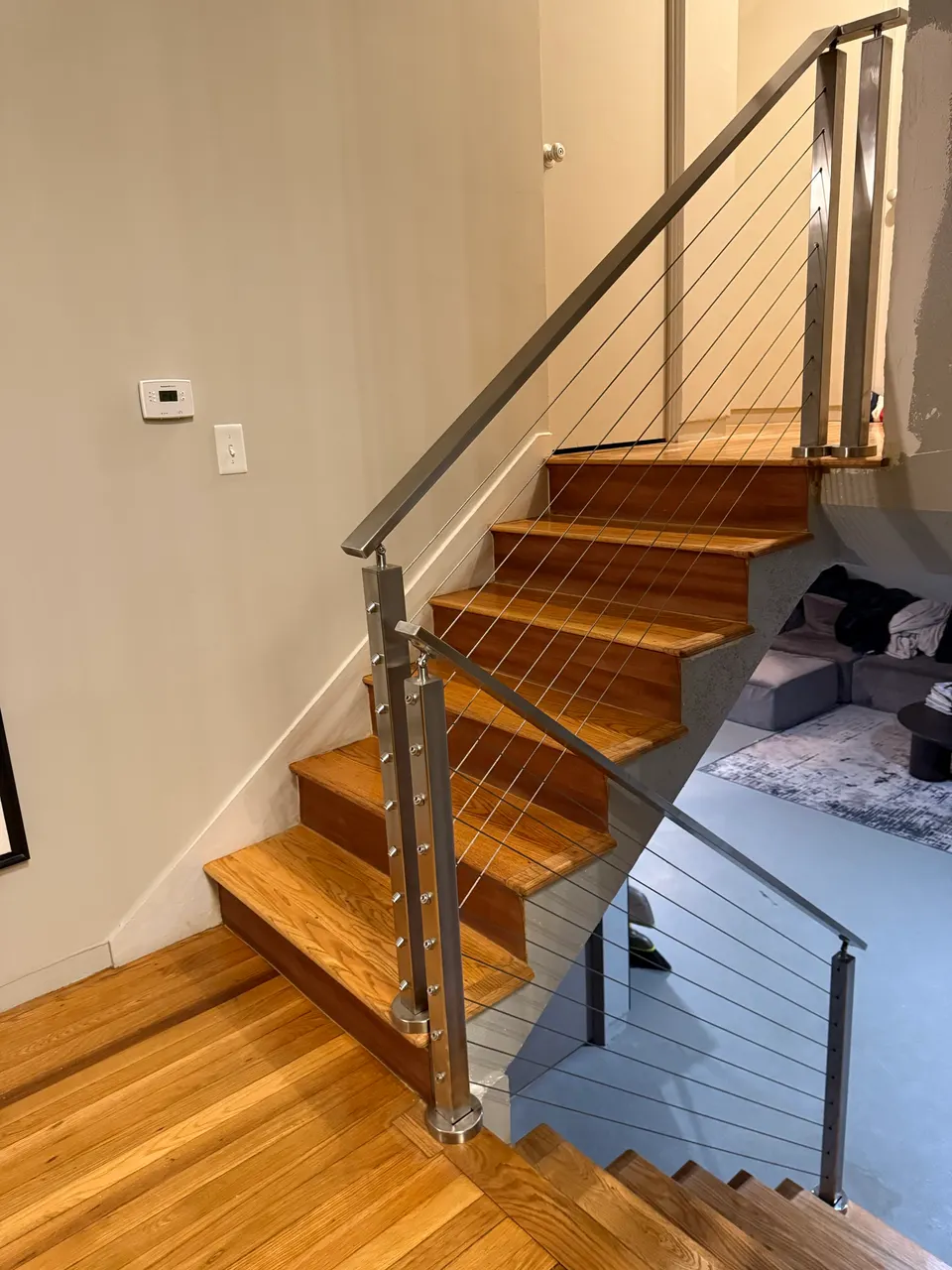 Stainless cable railing with a metal handrail beside a wood staircase