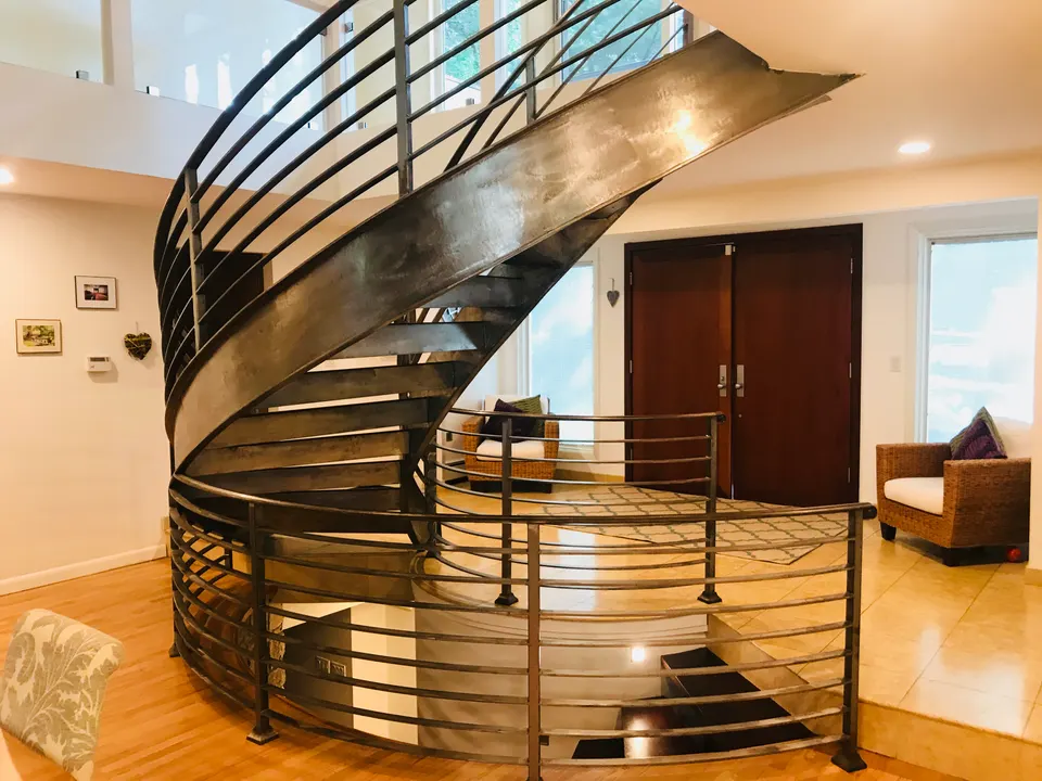 Curved steel stair with horizontal-bar railing in a living space