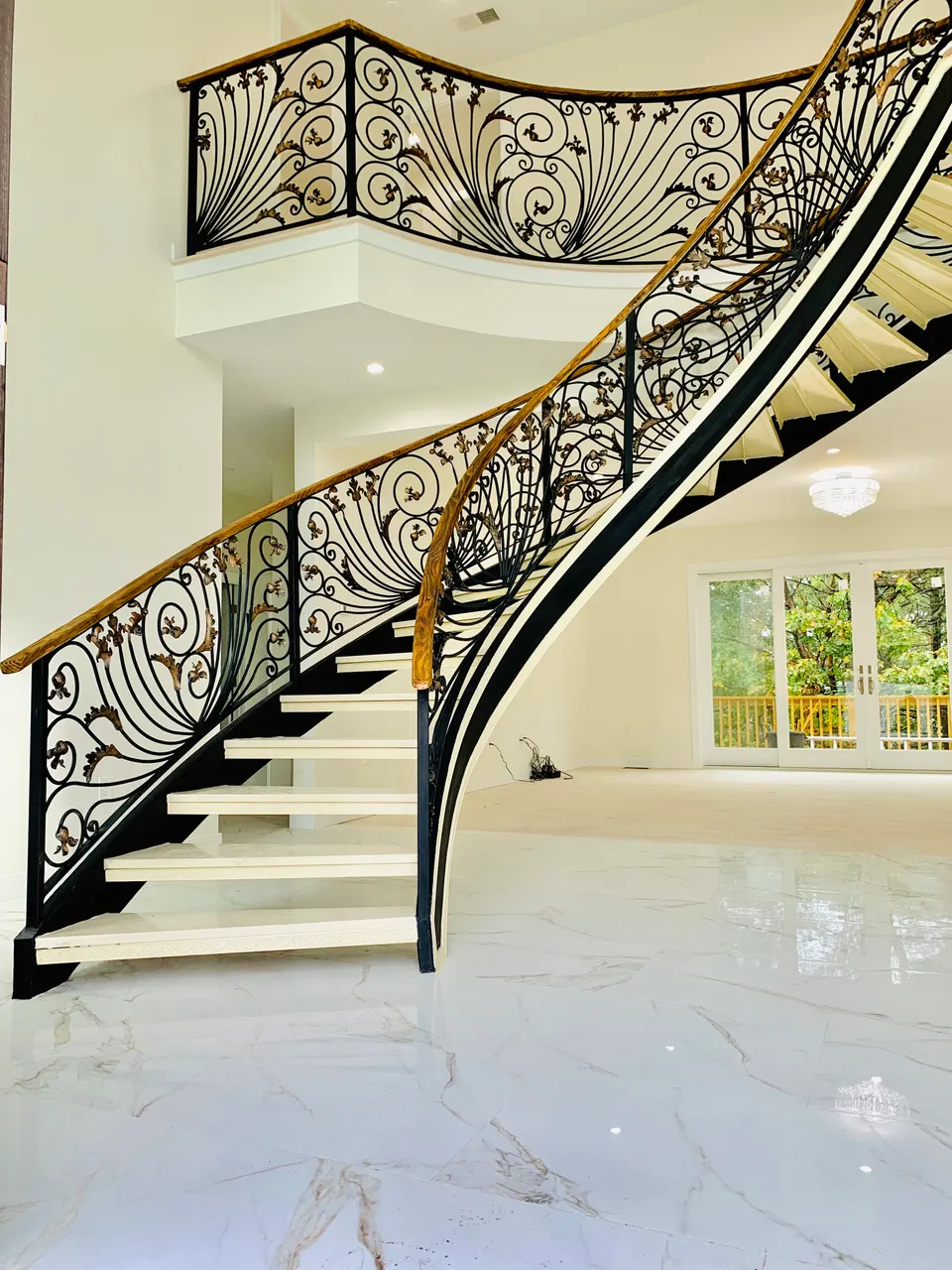 Curved staircase with an ornamental scroll balustrade and wood handrail