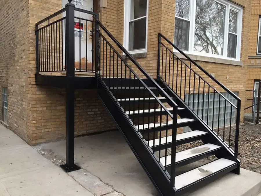 Black metal stairs and landing beside a brick building