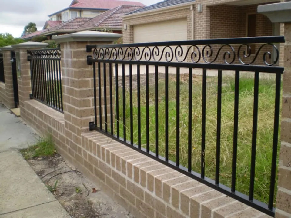 Black picket fence with scrollwork along the top, set on a low brick wall