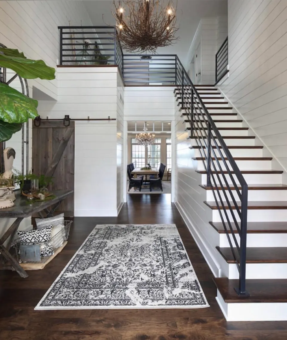 Black horizontal-bar railing along a staircase and upper landing in a bright entry hall