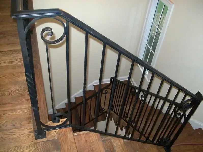 Black railing with scroll details over a wood staircase