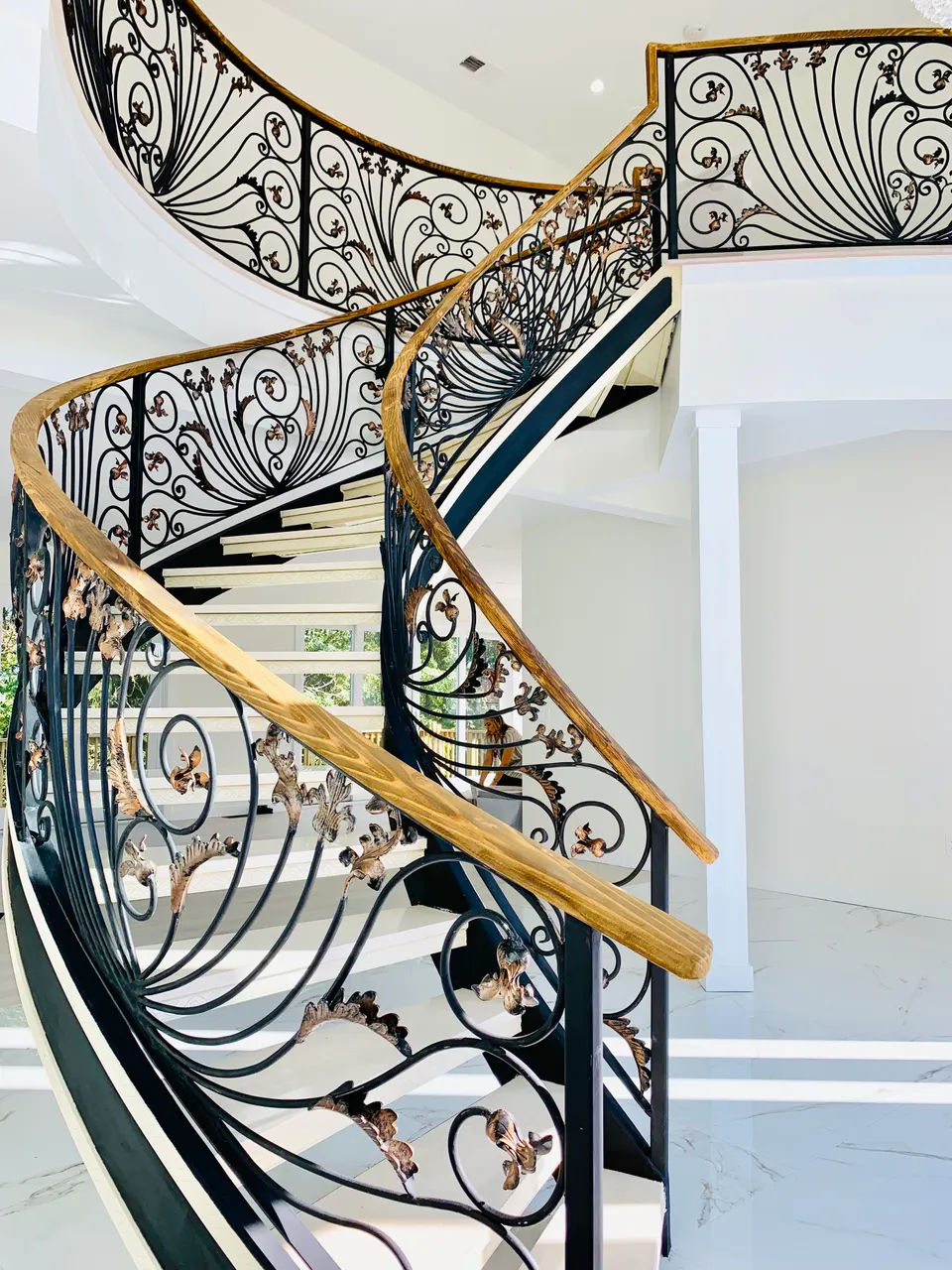 Ornamental scroll balustrade with a wood handrail along a curved stair
