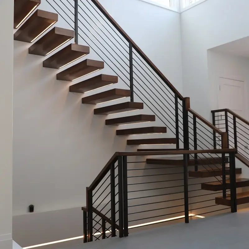 Black metal railing with horizontal detailing alongside an open wood staircase