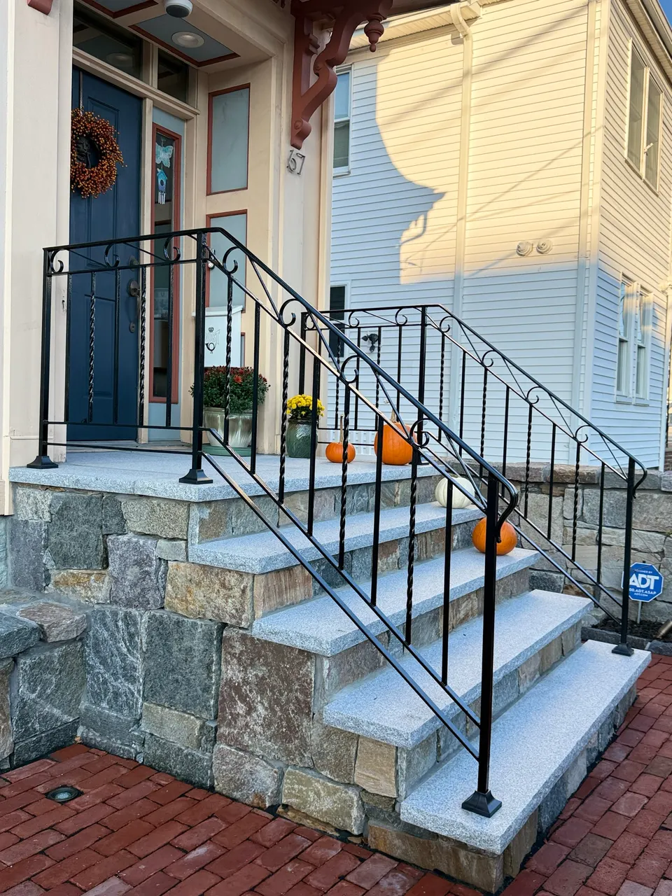 Black railings with scroll details on granite steps with a stone-faced base