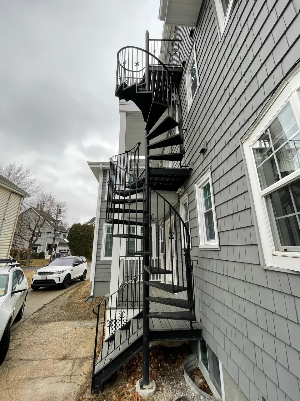 Black exterior spiral stair along gray shingle siding