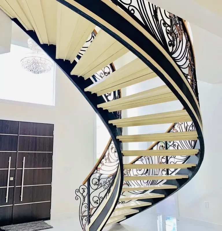 Curved staircase with flowing ornamental metal balustrade
